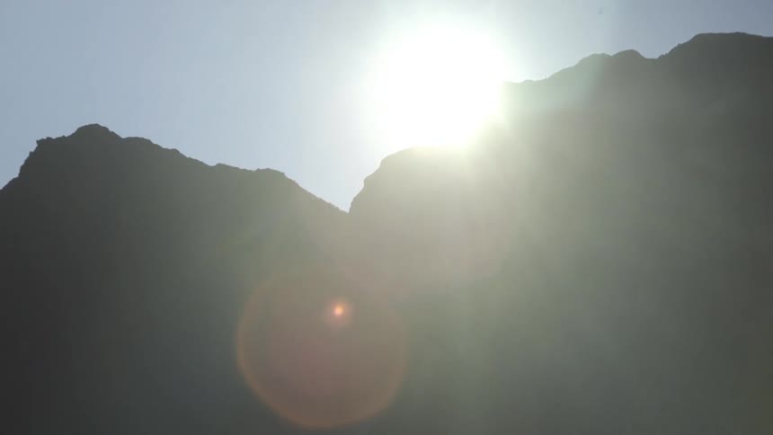 Silhouetted view of rocky hills with the sun in the background