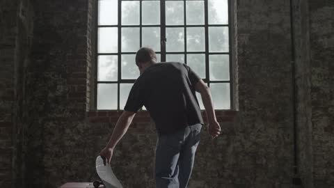 Man grabbing his skateboard and looking out the window