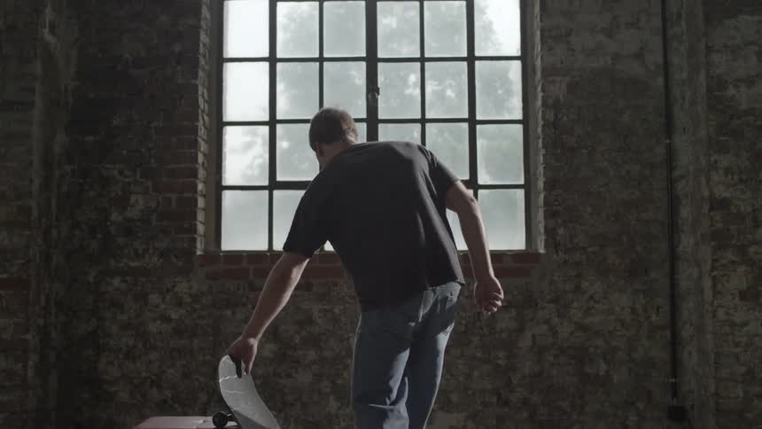 Man grabbing his skateboard and looking out the window