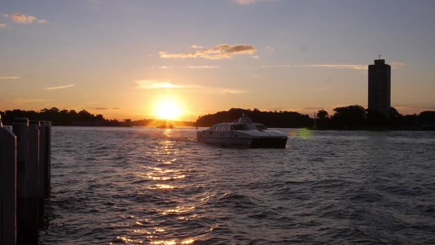 A boat travelling along the water as the sun sets in the background