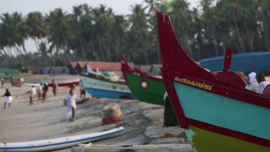 A man walks in front of parked boats on a beach
