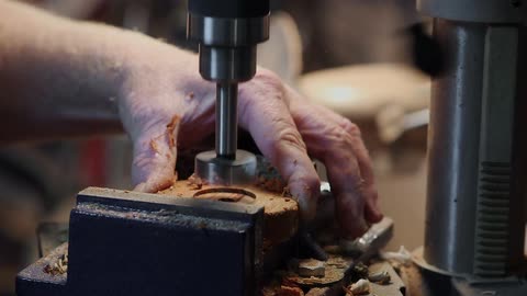 A man uses a drill press
