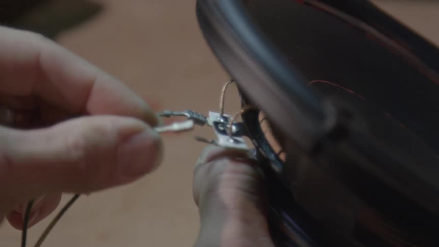 A person hooking speaker wire up to a speaker