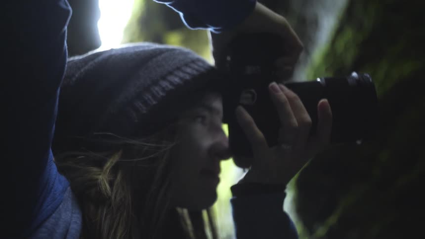 A woman adjusts her camera and takes a photograph