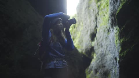 A woman in a canyon adjusts the settings of her camera and takes a photograph