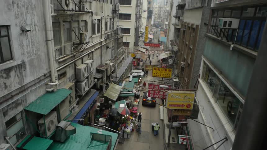 A car moving down a narrow street next to street vendors in an asian city