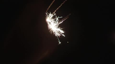 A hand holding sparklers that have burned low in the dark