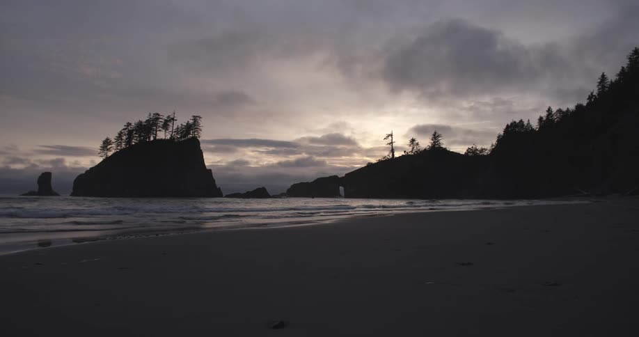 A vacant beach at dusk with cloudy skies