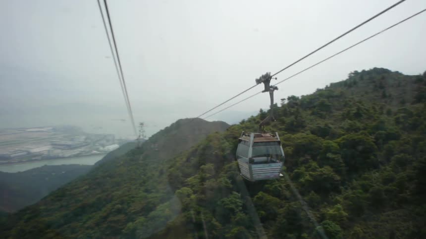A person rides a lift through the mountains