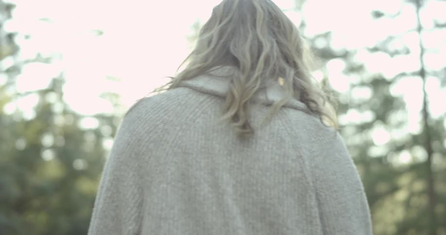 A woman walks in a sunny forest