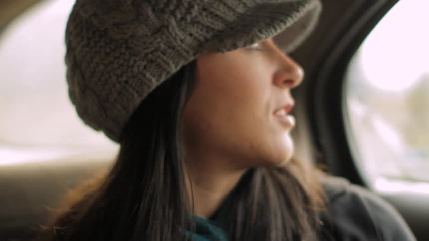 A young woman sitting in the back of a car
