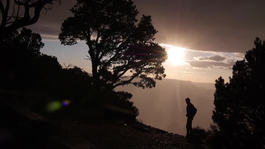 A man stands silhouetted against the sunny sky