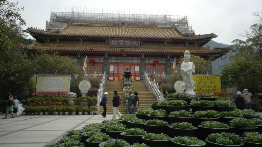 People walk near an asian building and garden