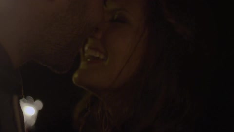 A young man kissing a laughing young woman while sparklers burn in the foreground