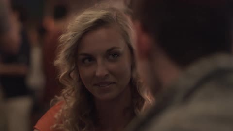 Blonde woman laughs and talks with a man in a busy restaurant