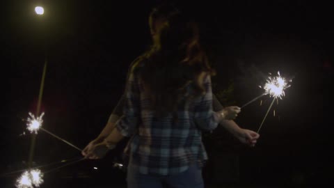 Man and woman running with sparklers and kissing