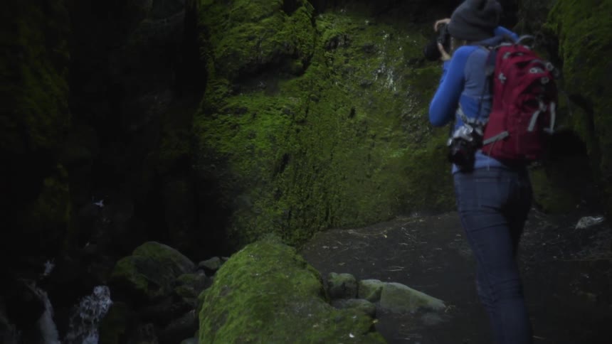 Person taking pictures of a waterfall while hiking