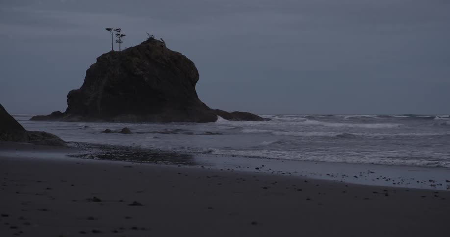 Waves crash onto beach at dusk