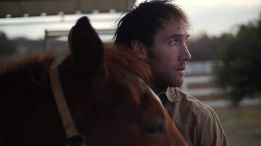 A  man is petting his horse
