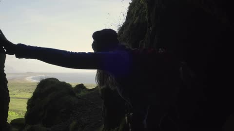 A woman hiking through a mountain with a stream of water going through below