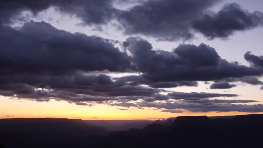 Dark clouds hovering over mountains at sunset