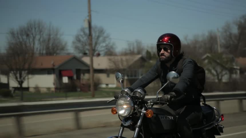 A man is driving his cycle down the road