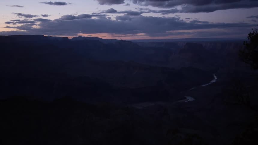 View of a winding river far below in a canyon at dusk or dawn