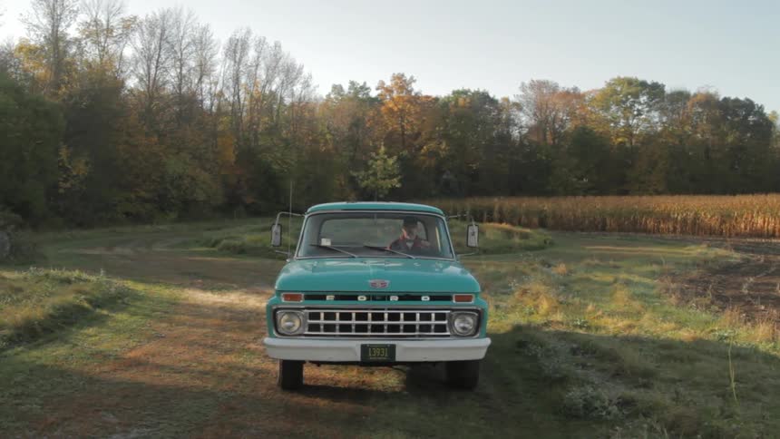 A man sits in an old blue truck