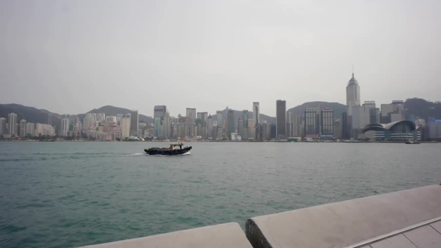 A boat moves on a lake with a city's skyline in the background