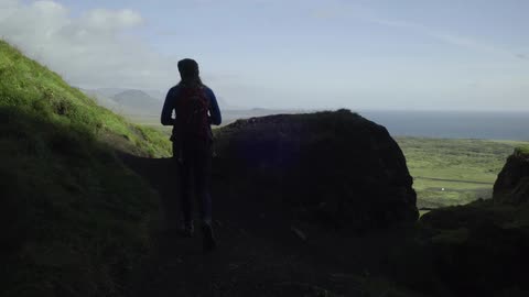 A woman hikes and stops to take a photograph