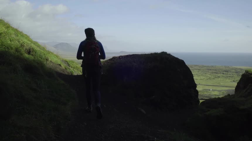 A woman hikes and stops to take a photograph