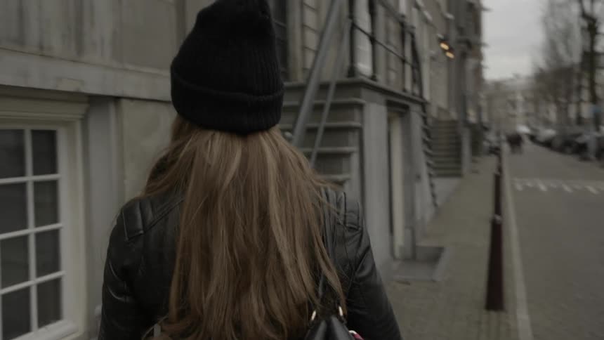 Woman casually strolling down a city street observing things