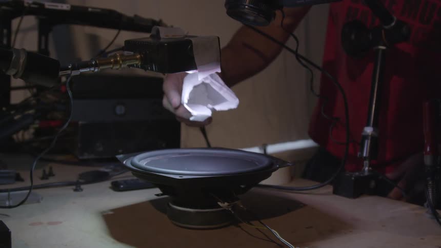 A person dropping some powder on the audio speaker