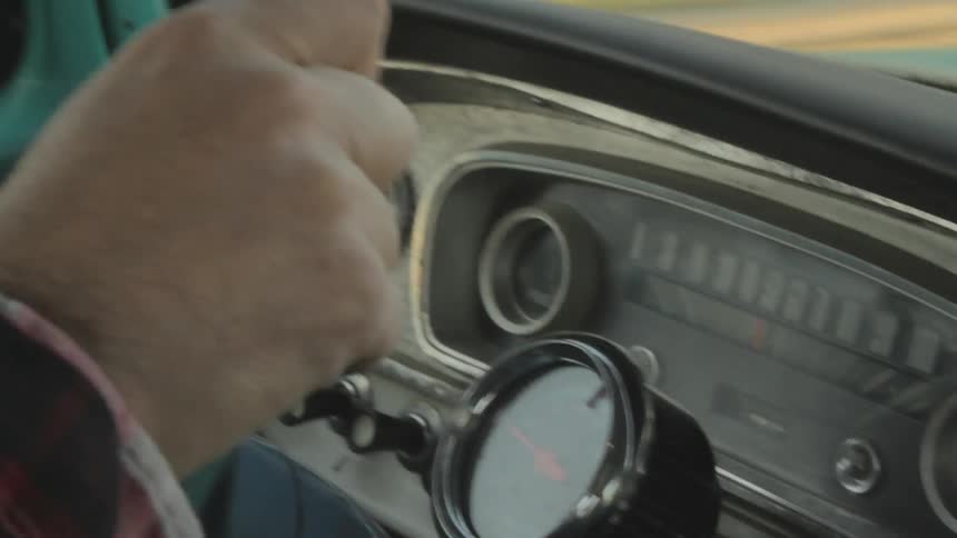 A man grasps a steering wheel and drives a vehicle