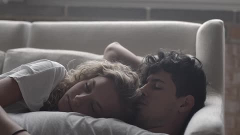 A man and woman cuddle on the couch