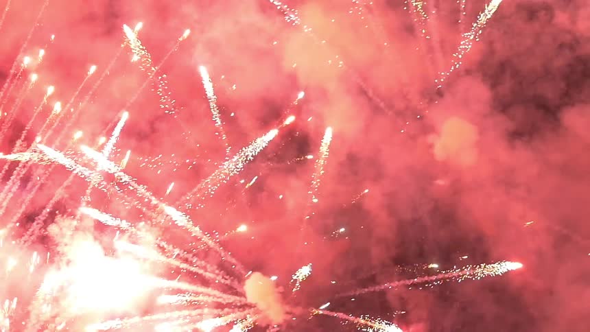 Fireworks are launched into the night sky and explode