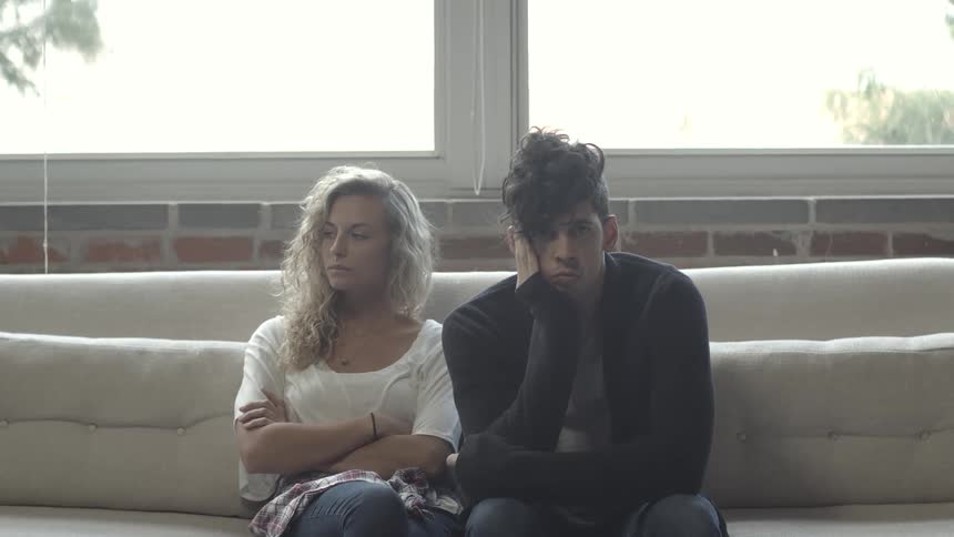 Man and woman sitting on couch looking upset