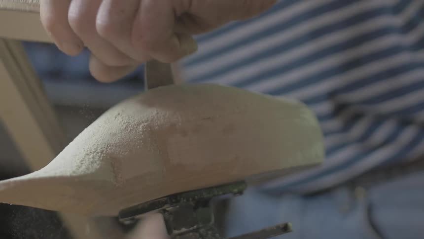 A man sands and smoothes a piece of wood