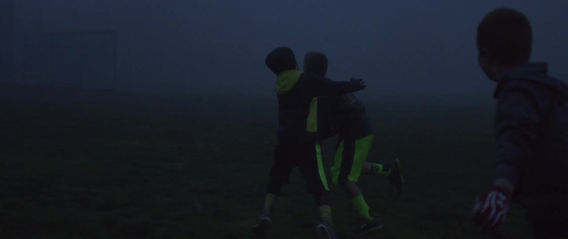 A group of boys playing football outside in the dark