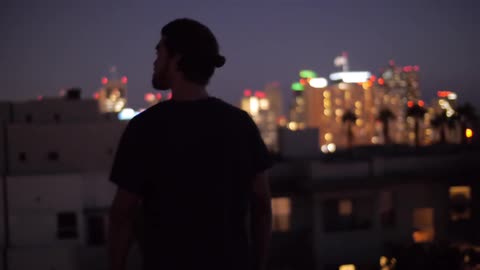 A man standing on the rooftop and looking around at the city view