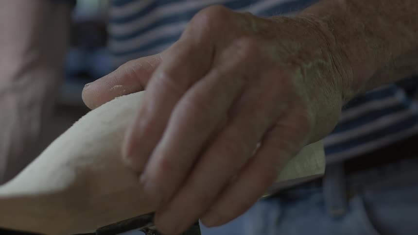 Close up of the hand of an older person working on a sculpture
