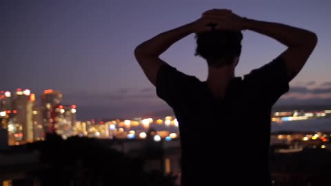 A man looks at the nighttime cityscape