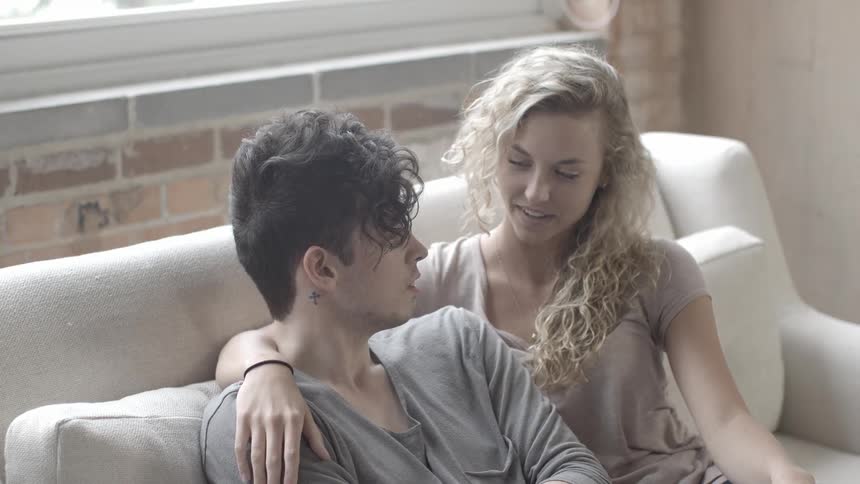 A man and woman chat and sit on a couch