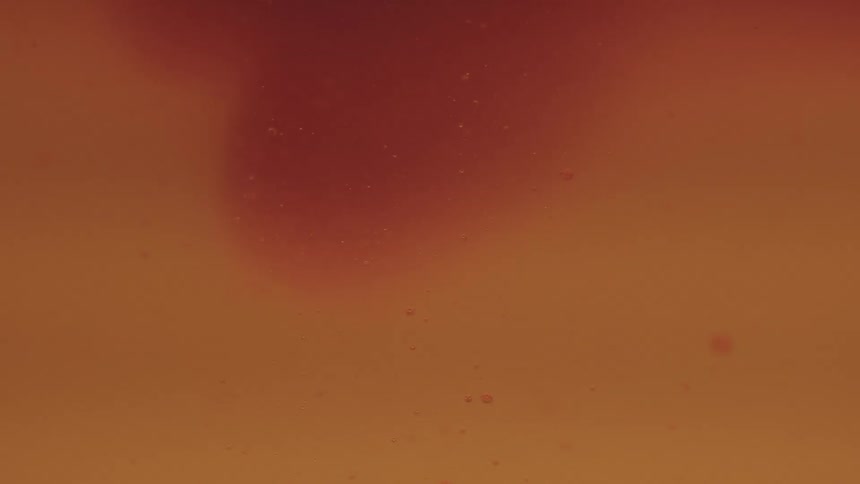 Particles floating in an orange colored liquid