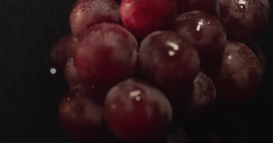 Mist sprays down on a bunch of red grapes