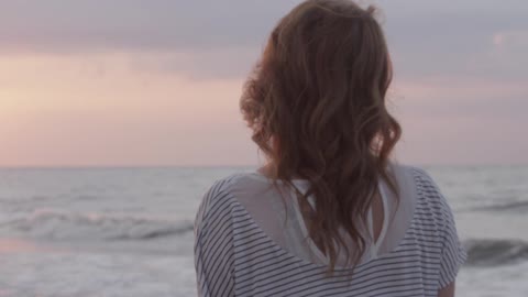 Three women walk towards the ocean at sunset