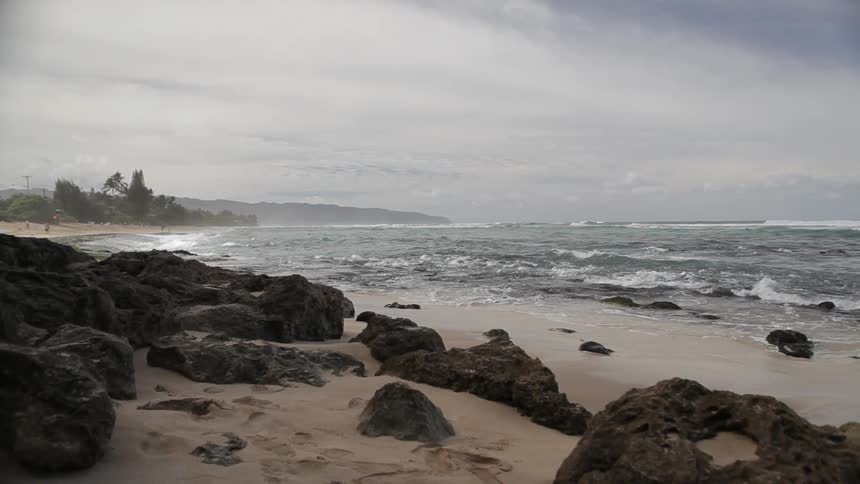 Rocks scatter a coastline as the waves crash