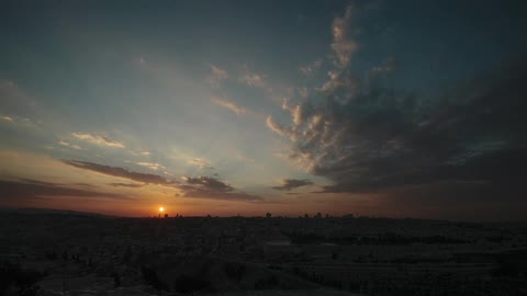 Clouds float over a city as the sun sets