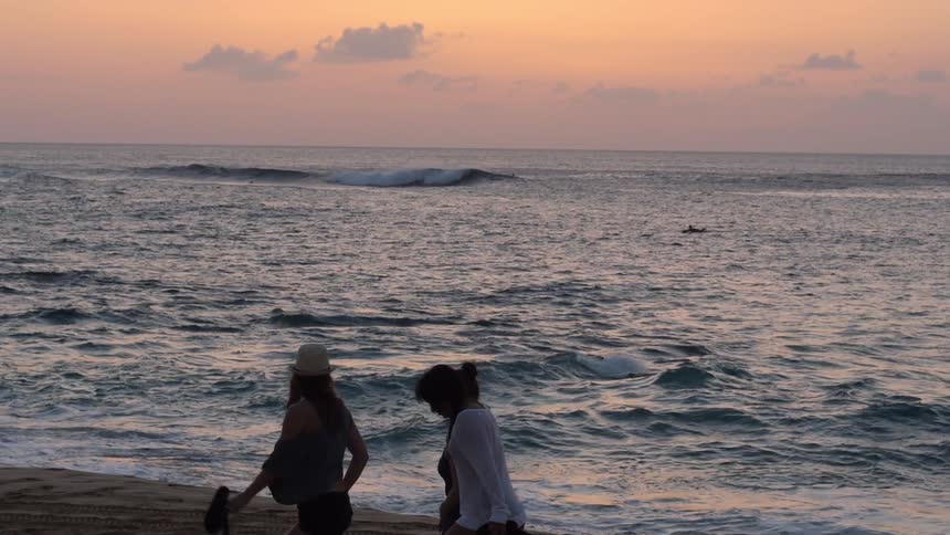 People walking on the beach during sunset