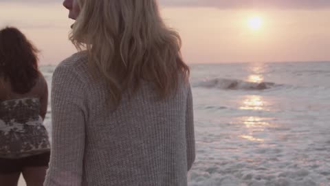 Women walk on the beach at sunset